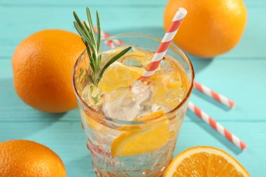 Açık mavi masada buzlu ve portakallı soda tazeleniyor, yakın plan.