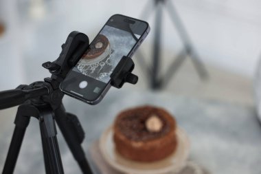 Stüdyoda akıllı telefonla çikolatalı pasta çekmek, seçici odaklanma. Profesyonel yemek fotoğrafçılığı.
