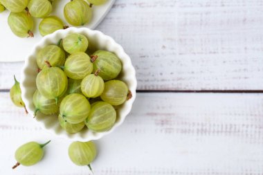 Taze yeşil bektaşi üzümleri kasede, beyaz ahşap masada, düz yerde. Metin için boşluk