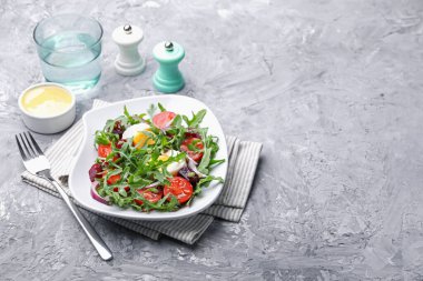 Lezzetli salata roka, sebze ve yumurta gri masada servis edilir, yazı için yer var.