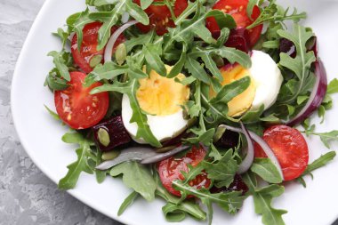 Lezzetli salata roka, sebze, yumurta ve tohumlar gri masada, üst manzara.