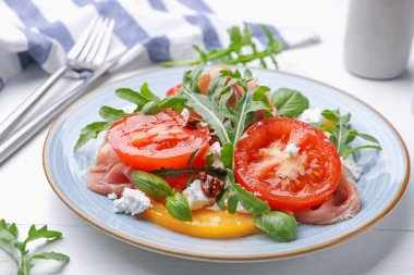 Beyaz ahşap masada roka, peynir, domates, fındık ve prosciutto ile lezzetli salata.