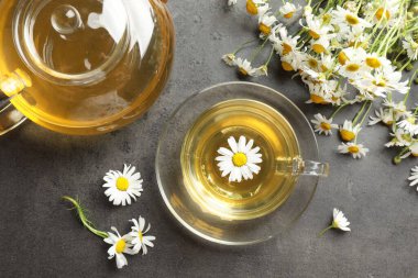 Lezzetli papatya çayı ve çiçekler gri masada, düz yatıyordu.