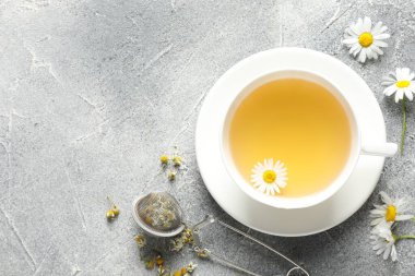 Lezzetli papatya çayı, zerk makinesi ve açık gri masada çiçekler, düz yatak. Metin için boşluk