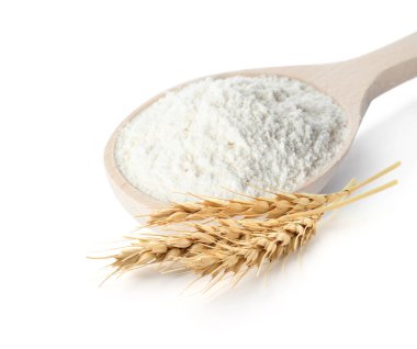Kaşık içinde buğday unu ve beyaz arka planda dikenler.