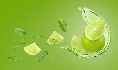 Taze limonlar, yapraklar ve içecekler yeşil arka planda havada sıçrıyor.