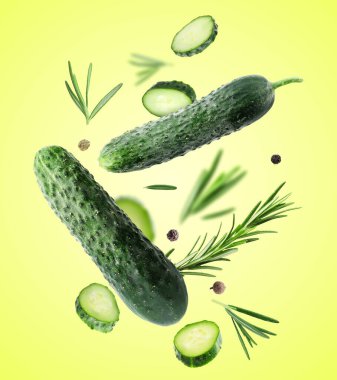 Taze salatalıklar, biberiye ve biber taneleri sarı arka plana dökülüyor.