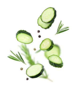 Salatalık dilimleri, biberiye ve biber taneleri beyaz arka plana düşüyor.