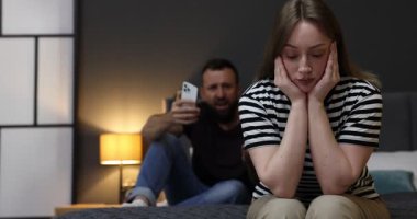 İhanet. Akıllı telefonlu kızgın bir adam evde yaralı karısına bağırıyor, seçici bir şekilde.