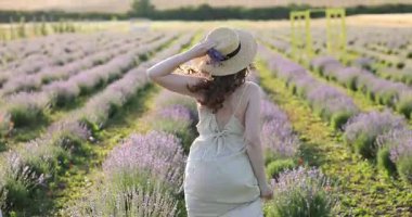 Hasır şapkalı kadın lavanta tarlasında koşuyor ve güzel çiçekler kokuyor.