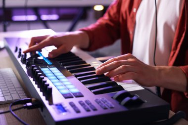 İçerideki masada MIDI klavyesiyle çalışan adam, yakın plan.