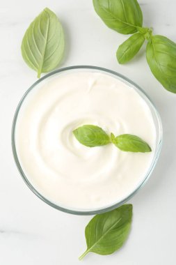 Lezzetli yoğurt ve fesleğen beyaz masada, düz yerde.