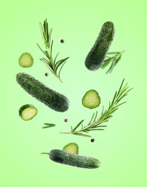 Taze salatalıklar, biberiye ve biber taneleri açık yeşil arka plana düşüyor.