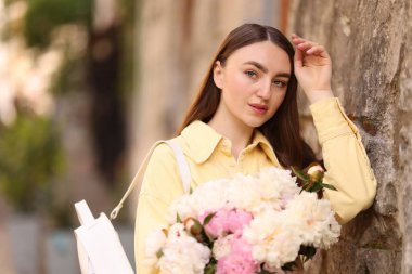 Şehir caddesinde elinde şakayık demeti olan bir kadın