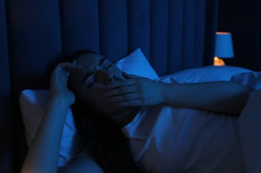 Evde yatakta uykusuzluk çeken hayal kırıklığına uğramış bir kadın.