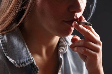 Arka planda sigara içen tişörtlü bir kadın, yakın plan. Kötü alışkanlık.