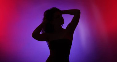 Renkli arka planda neon ışıklarla poz veren kadın silueti