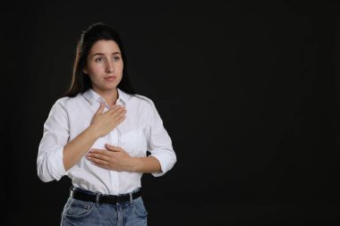 Panik atak. Siyah arkaplanda sakinleşmek için nefes alan kadın, metin için alan