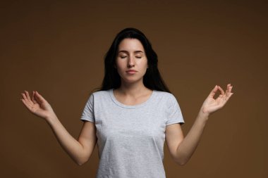 Panik atak. Kahverengi arka planda sakinleşmek için meditasyon yapan kadın