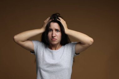 Kahverengi arka planda panik atak geçiren endişeli bir kadın.