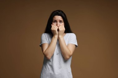 Kahverengi arka planda panik atak geçiren endişeli bir kadın.