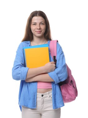 Sırt çantası ve beyaz arka planda defterleri olan genç bir kız.
