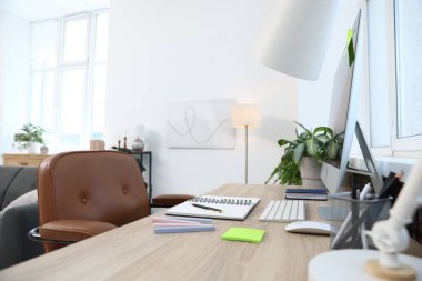 Ofisteki ahşap masada modern bilgisayar ve kırtasiye malzemeleri, yakın çekim. Rahat bir iş yeri