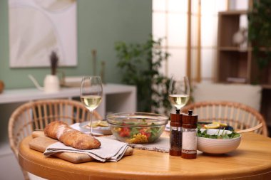 İçinde lezzetli yemekler ve beyaz şarap olan bir yemek masası.