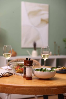 İçinde lezzetli yemekler ve beyaz şarap olan bir yemek masası.
