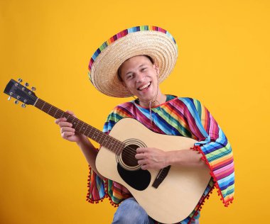 Şapkalı mutlu adam ve sarı arka planda gitar çalan renkli panço.