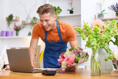 Dükkandaki ahşap masada çalışan bir buket çiçekli profesyonel çiçekçi.