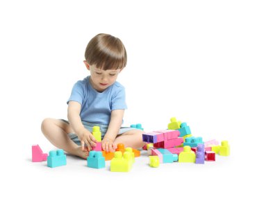 Beyaz arka planda tuğlalarla oynayan sevimli küçük çocuk.