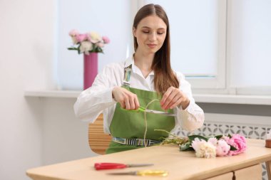 Çiçekçinin ahşap masasında şakayık buketi yapan bir çiçekçi.