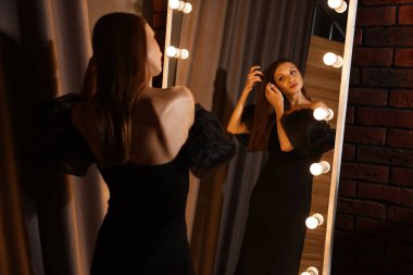 Güzel bir kadın aynanın yanında hazırlanıyor.