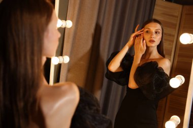 Güzel bir kadın aynanın yanında hazırlanıyor.