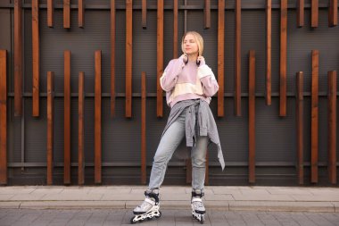 Açık hava binasının yakınında patenli güzel genç bir kadın.