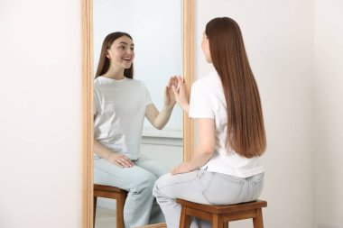 Güzel bir kadın aynada kendine bakıyor.