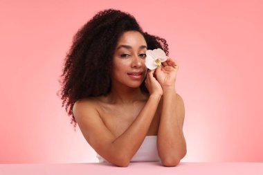 Pembe gradyan üzerinde orkide çiçekli güzel Brezilyalı kadın portresi.