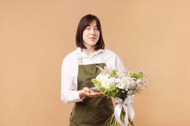 Bej arka planda güzel bir buket çiçekli çiçekçi.