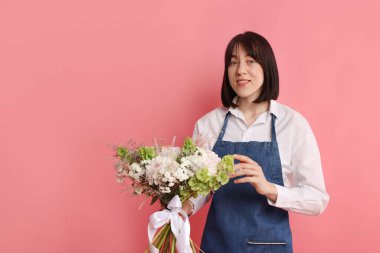 Pembe arka planda çiçek buketi olan bir çiçekçi, mesaj için yer.