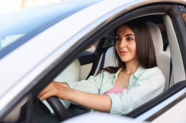 Araba kullanırken direksiyon tutan kadın, dışarıdan görüyor