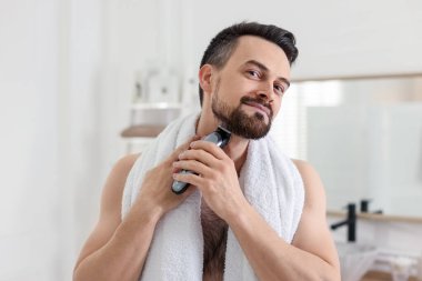 Yakışıklı adam banyoda tıraş makinesiyle tıraş oluyor.