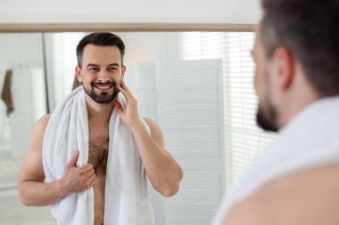 Banyoda aynaya bakarken tıraş olmadan önce gülümseyen adam.