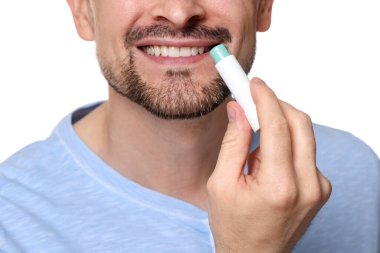 Gülümseyen adam dudaklarına merhem sürüyor. Beyaz arka planda, yakın plan.