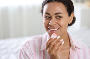 Bulanık arka planda dudak kremi olan gülümseyen bir kadın. Metin için boşluk