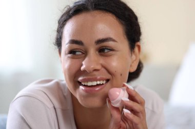 Arka planda dudak kremi olan gülümseyen kadın, yakın plan.