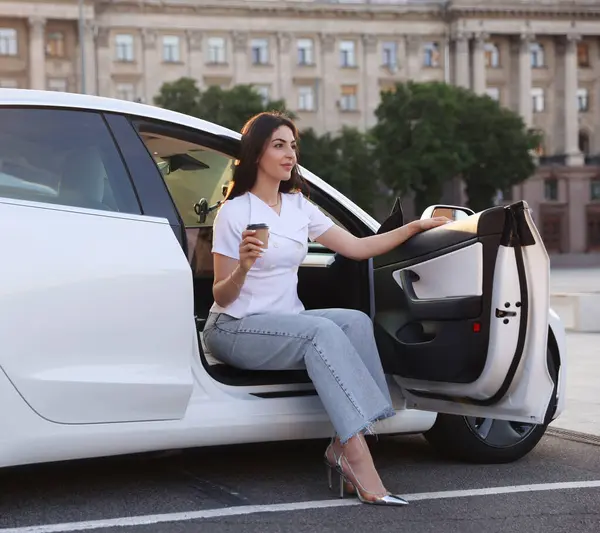 Kahveli kadın modern arabadan dışarı çıkıyor.