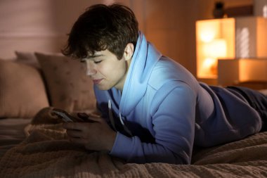 Ergen çocuk evde akıllı telefon kullanıyor.