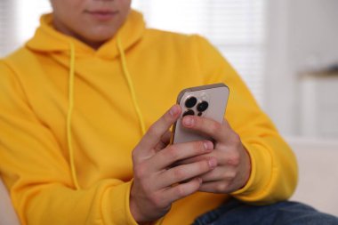 Ergen çocuk evde akıllı telefon kullanıyor, yakın plan.