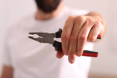 Kapalı mekanda pense giyen adamın yakın görüntüsü.